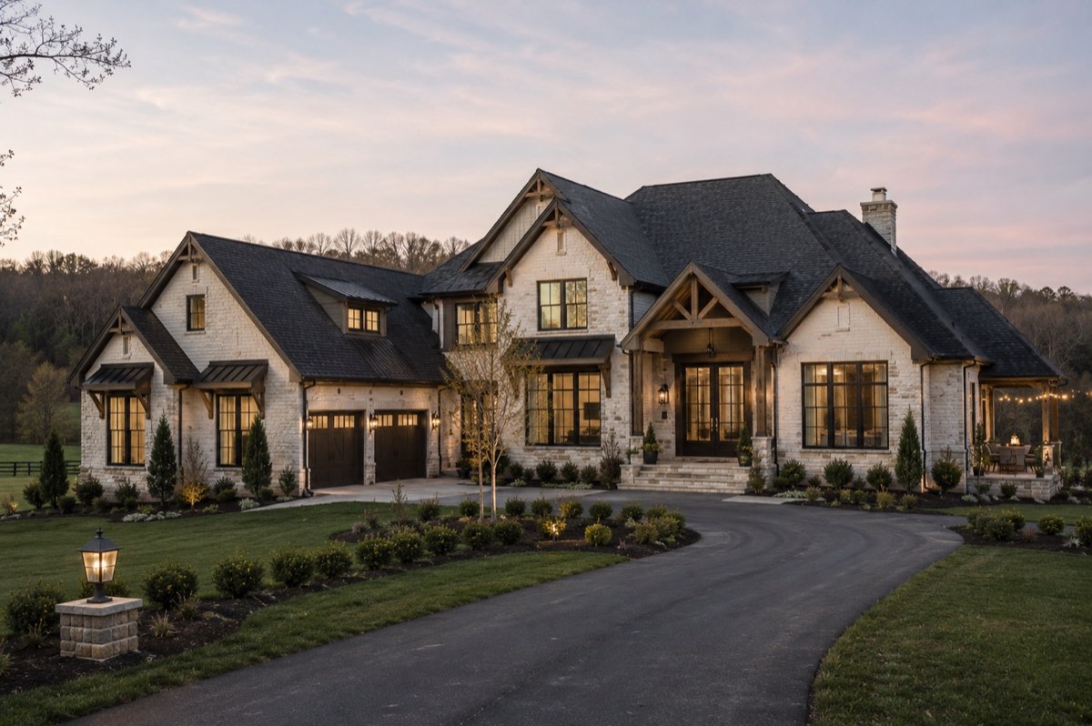 Stone and timber custom home at dusk, with a gabled roofline, a covered timber entry and lit windows