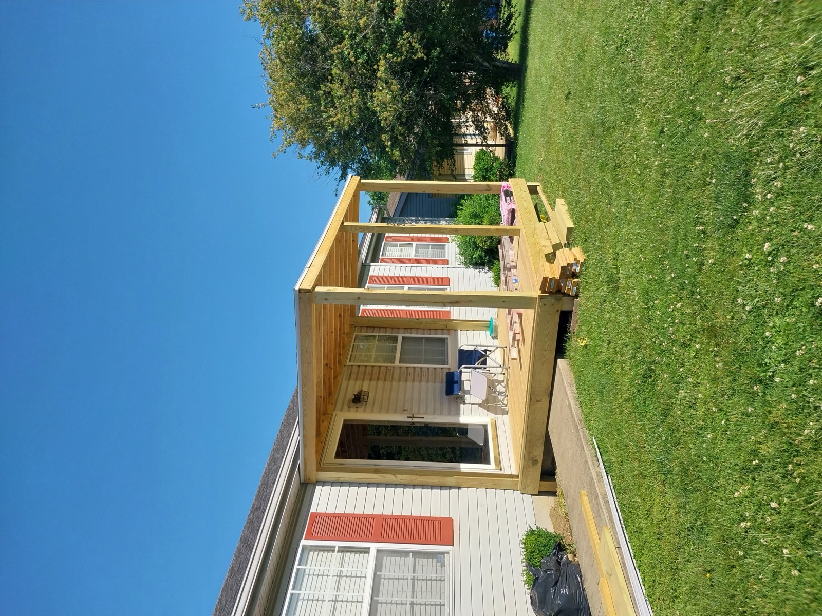 The same front entry finished with a new covered porch, cedar posts and a shingled roof over a wooden deck