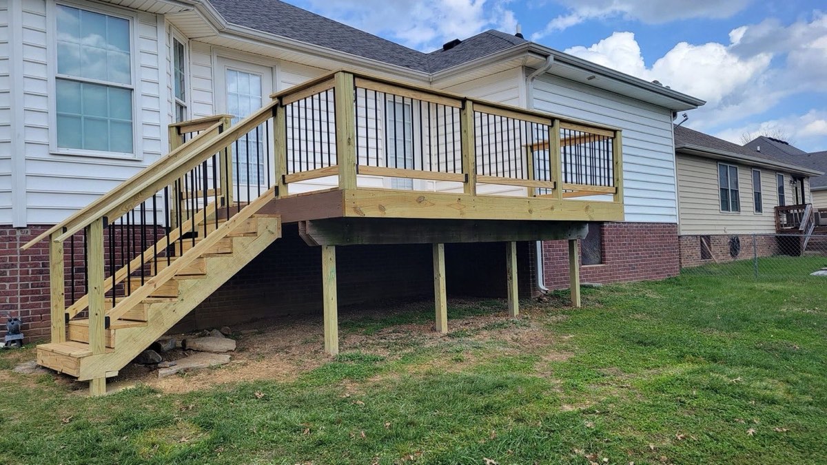 Elevated pressure-treated deck with black steel balusters and a full staircase on a Danville area home