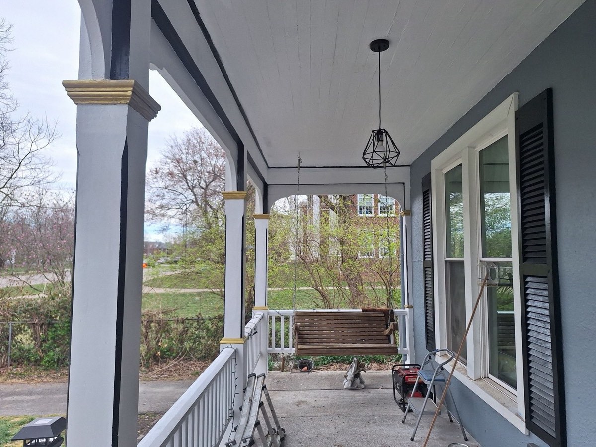 Finished porch on a restored historic home with repainted columns, gold capital accents, and new lighting
