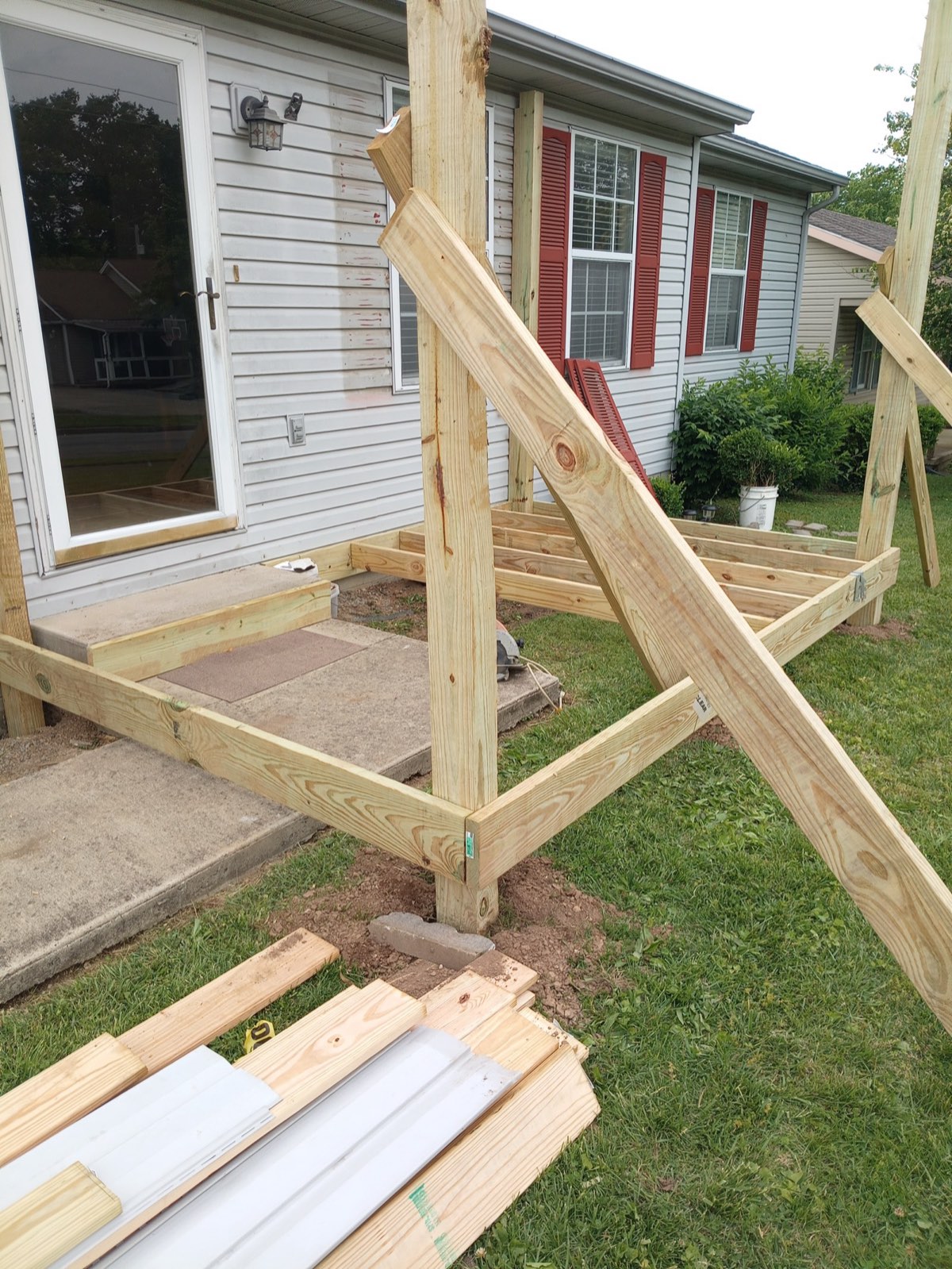 Close-up of new pressure-treated deck framing with rim joists, post connections, and bracing during a Scott Construction build